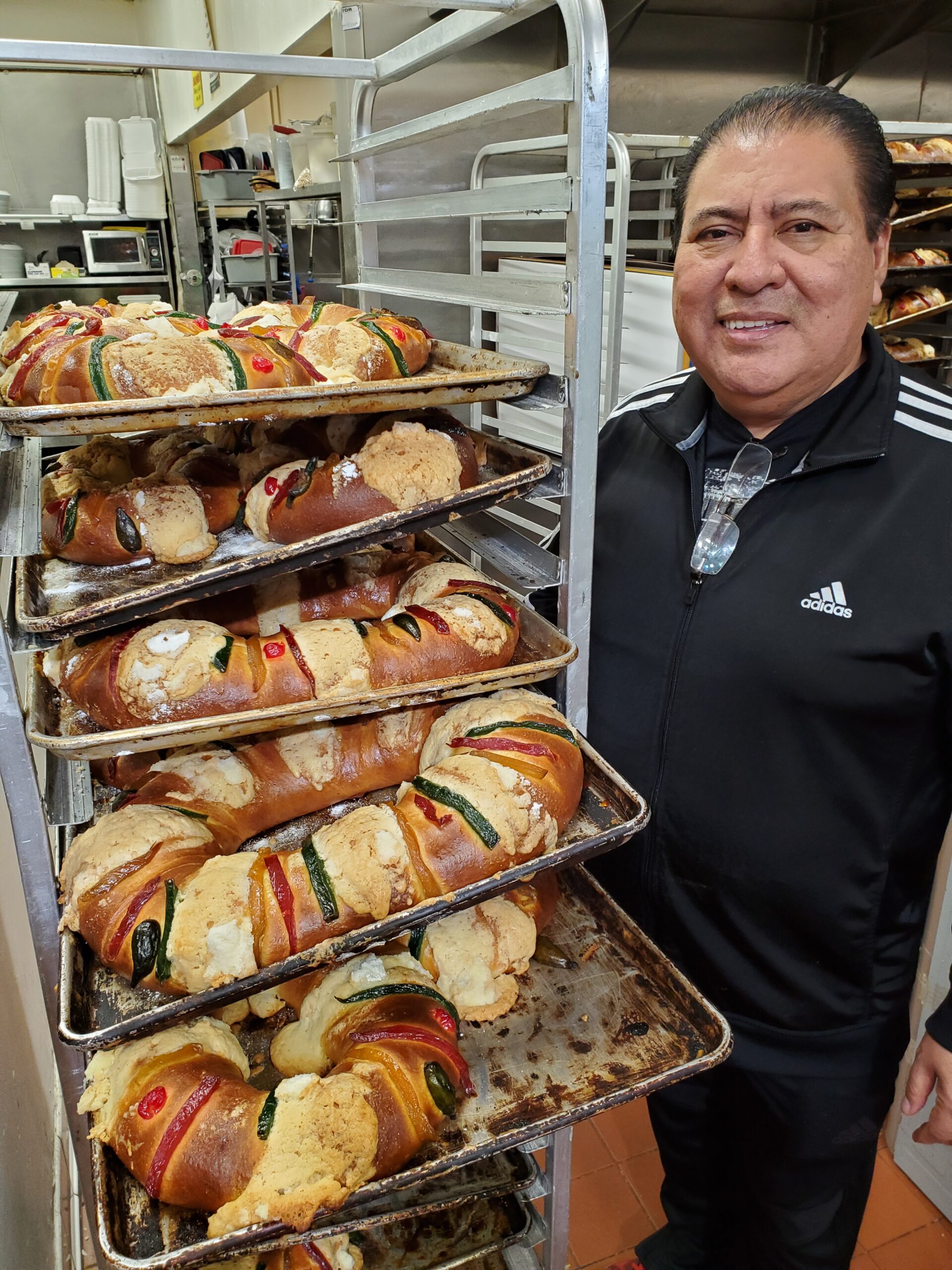 Man smiling in front of a rack of freshly baked bread